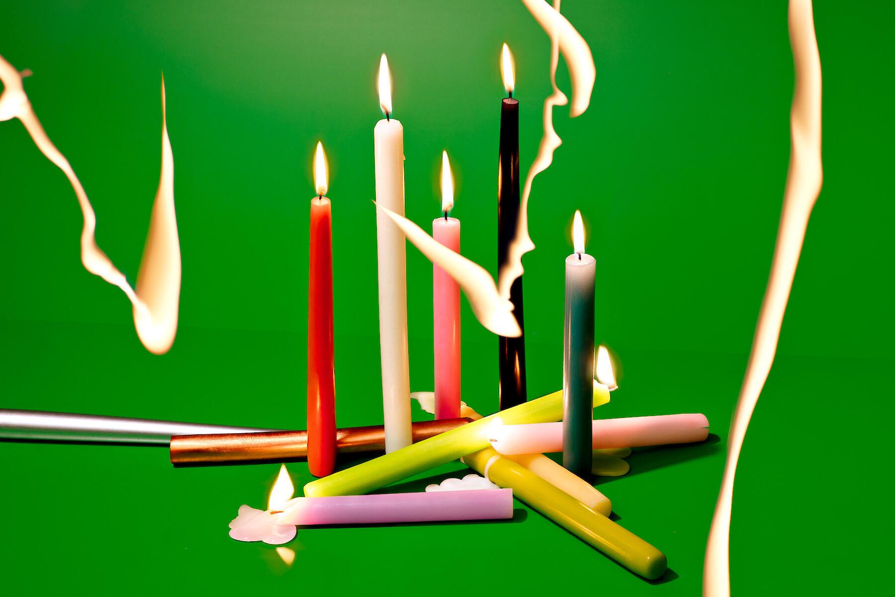 Colourful candles on a green background with light drawing
