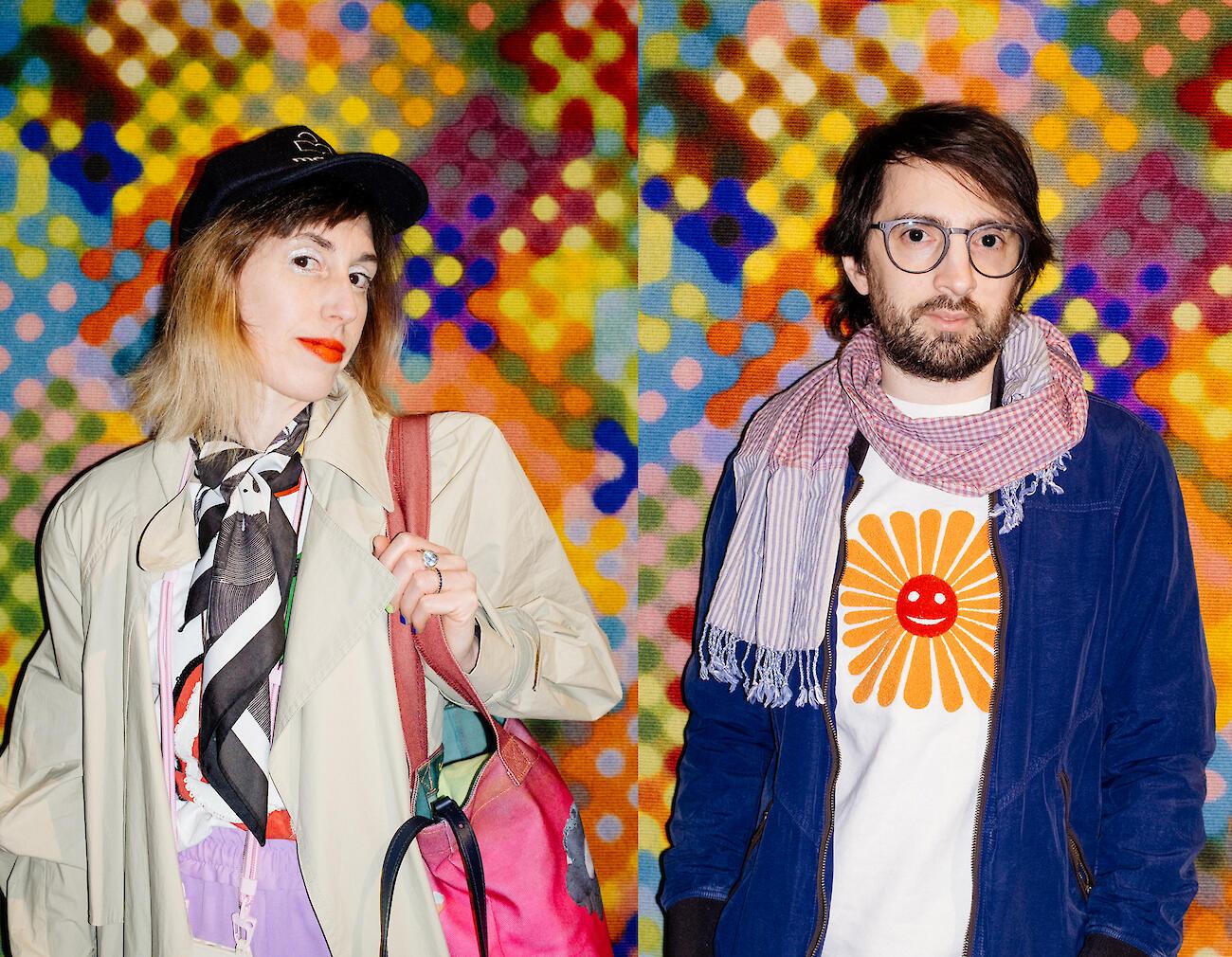 Maya & Daniele in front of a colorful, blurred mosaic background