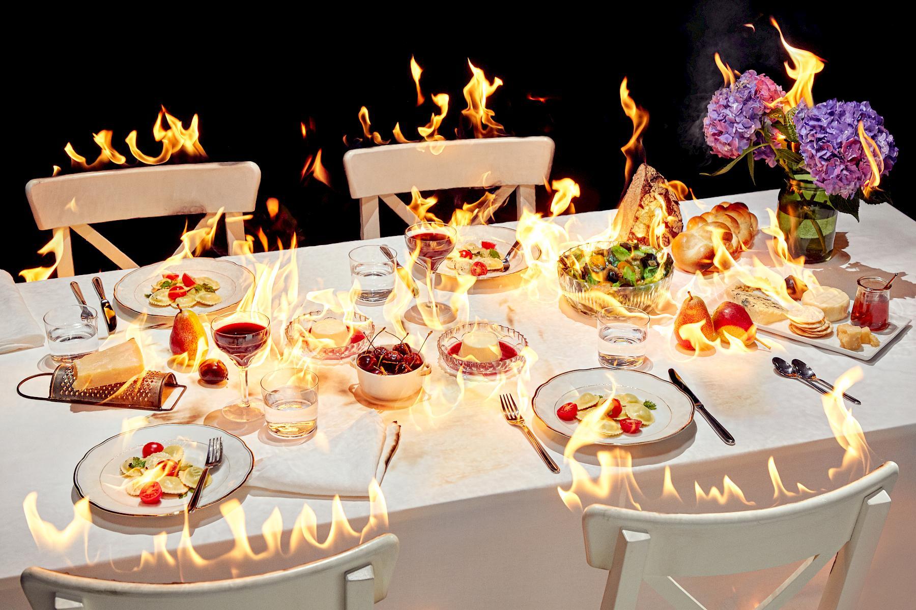 A still life of a burning table with food and drinks