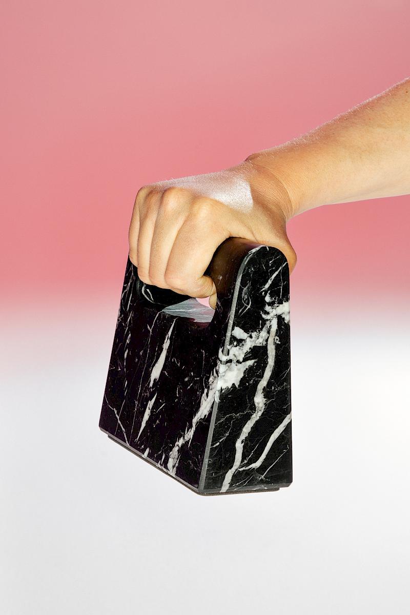 A male hand holding a 5KG single block of Granite. Design by Tobias Brunner, Bureau Brunner Industrial Design